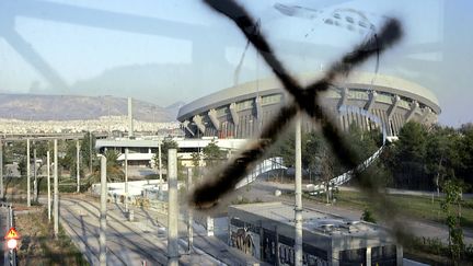 Un tag sur la vitre du pont a&eacute;rien qui m&egrave;ne vers le stade de la paix et de l'amiti&eacute;, &agrave; Ath&egrave;nes. Cette enceinte, qui a co&ucirc;t&eacute; des centaines de millions d'euros, n'a pratiquement plus servi depuis les Jeux olympiques d'Ath&egrave;nes, en 2004. (LOUISA GOULIAMAKI / AFP)