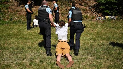 Des gendarmes éloignent du parcours de la course des&nbsp;militants écologistes du mouvement Derniere rénovation, lors de la 10e étape du Tour de France dans les Alpes françaises, le 12 juillet 2022. (MARCO BERTORELLO / AFP)