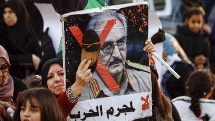 Une manifestante frappe avec une chaussure le portrait du maréchal Haftar, à Tripoli, le 27 décembre 2019. (MAHMUD TURKIA / AFP)