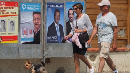 Des habitants passent devant des affiches pour les élections législatives à Saint-Cyprien (Pyrénées-Orientales), le 6 juin 2017. (RAYMOND ROIG / AFP)