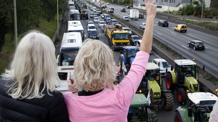 Les agriculteurs empruntent le p&eacute;riph&eacute;rique pour entrer dans la capitale. Deux passantes leur font signe au dessus d'un pont.&nbsp; ( CHARLES PLATIAU / REUTERS)