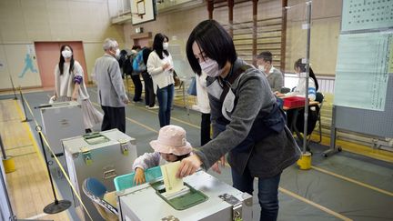 Une électrice japonaise glisse un bulletin dans l'urne lors de l'élection de la chambre basse du parlement, le 31 octobre 2021 à Tokyo (Japon). (FRANCK ROBICHON / EPA)