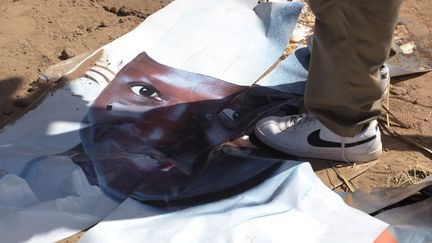 Un homme piétine une affiche électorale déchirée du président gambien sortant, Yahya Jammeh, dans une rue de Bijilo, le 4 décembre 2016 (SEYLLOU / AFP)