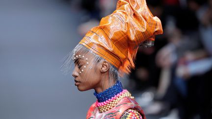 Coiffées d'un turban, les mannequins ont le visage et les bras parsemés de motifs réalisés avec des perles blanches qui ne sont pas sans évoquer les tatouages. Autour du cou, des colliers tissés en matières plastiques, et à la main des petits sacs sphériques en forme de planètes. 
 (PATRICK KOVARIK / AFP)