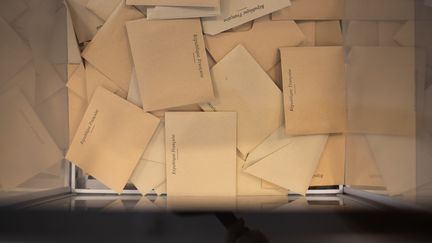 Des enveloppes avec les bulletins de vote dans une urne à Lyon, le 20 juin 2021, pour le premier tour des régionales. (SABINE GREPPO / HANS LUCAS / AFP)