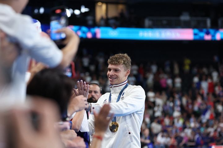 Léon Marchand, avec sa quatrième médaille d'or autour du cou, célèbre avec ses supporters sa victoire sur le 200 m 4 nages des Jeux olympiques de Paris, le 3 août 2024, à la Paris La Défense Arena. (COUVERCELLE ANTOINE / KMSP)