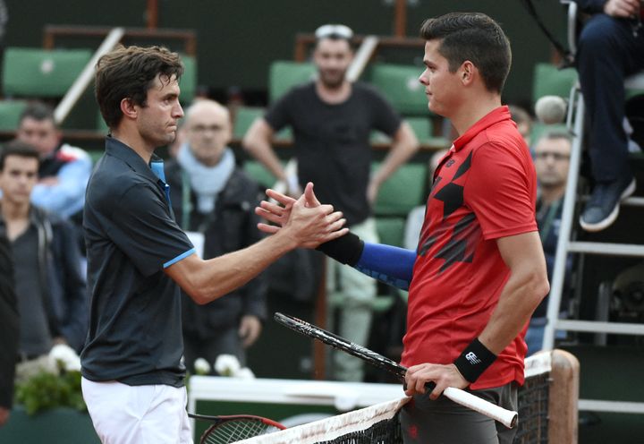 Gilles Simon et Milos Raonic se serrent la main après la victoire du Canadien au troisième tour de Roland-Garros, le 30 mai 2014. (PASCAL GUYOT / AFP)