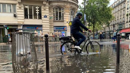 Un cycliste passe après l'orage dans la rue du Faubourg-Saint-Antoine inondée, dans le 12e arrondissement de Paris, le 16 août 2022. (MAXPPP)