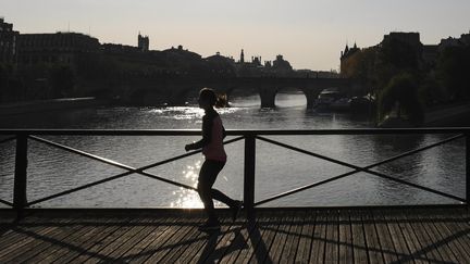 Une femme court sur le Pont des Arts, à Paris, le 8 avril 2020. (ALAIN JOCARD / AFP)