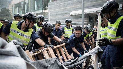 Des policiers de Hong Kong d&eacute;montent, mardi 14 octobre,&nbsp;des barricades &eacute;rig&eacute;es par les manifestants qui r&eacute;clament un suffrage d&eacute;mocratique en 2017. (PHILIPPE LOPEZ / AFP)