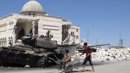 De jeunes syriens passent &agrave; c&ocirc;t&eacute; d'un char abandonn&eacute; devant la mosqu&eacute;e d'Azaz (Syrie), le 20 ao&ucirc;t 2012. (BEN HUBBARD / AP / SIPA)