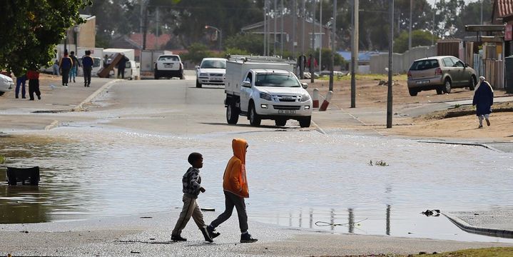 Des enfants passent devant une flaque d'eau après de fortes pluies au Cap, le 26 avril 2018. (REUTERS/Sumaya Hisham)