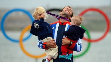 Nick Dempsey, m&eacute;daill&eacute; d'argent en voile, sur le podium olympique avec ses enfants, le 7 ao&ucirc;t 2012.&nbsp; (WILLIAM WEST / AFP)