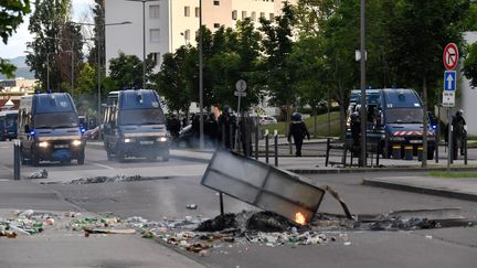 Des gendarmes se tiennent près de leurs véhicules alors que brûlent des ordures dans les rues du quartier des Grésilles, à Dijon (Côte-d'Or), le 15 juin 2020. (PHILIPPE DESMAZES / AFP)