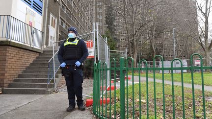 Un policier monte la garde à l'extérieur d'un lotissement public qui fait l'objet d'un confinement forcé à Melbourne le 10 juillet 2020. (WILLIAM WEST / AFP)