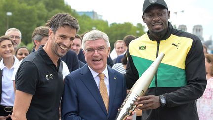 Thomas Bach, le président du CIO, au milieu de Tony Estanguet et Usain Bolt, le 26 juillet 2023, à Paris. (ALAIN JOCARD / AFP)