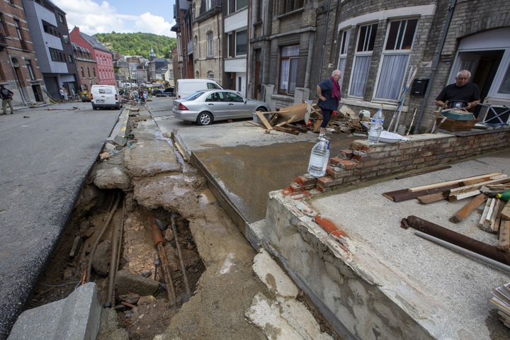 Des résidents de Dinant, en Belgique, constatent les dégâts devant leur domicile, où une rue a été détruite par les inondations, le 25 juillet 2021. (NICOLAS MAETERLINCK / BELGA / AFP)