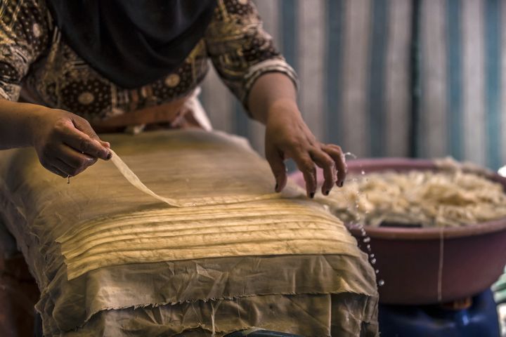 Une femme étend des fines bandes mouillées de papyrus pour faire une feuille, dans le village de al-Qaramous.&nbsp; (KHALED DESOUKI / AFP)