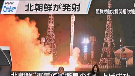 Des piétons devant un écran montrant des images évoquant le lancement d'un satellite par la Corée du Nord, à Tokyo, la capitale japonaise, le 22 novembre 2023. (KAZUHIRO NOGI / AFP)