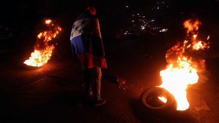 Pour soutenir la démarche des migrants partis rejoindre la "caravane", des manifestants ont enflammé des pneus devant l'ambassade américaine à Tegucigalpa (Honduras), le 19 octobre 2018. (AFP)