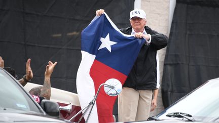 Le président américain Donald Trump brandit un drapeau du Texas lors de sa visite dans la ville sinistrée de Corpus Christi, le 29 août 2017, après le passage de la tempête Harvey. (JIM WATSON / AFP)