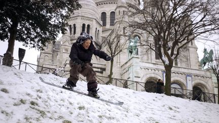 Un jeune snowboardeur profite des pentes enneig&eacute;es de la butte Montmartre &agrave; Paris, le 12 mars 2013. (FRED DUFOUR / AFP)