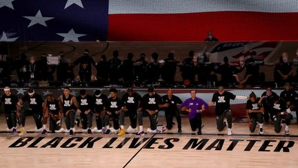 Des joueurs des Lakers et des Clippers posent un genou à terre, le 30 juillet 2020, en Floride. (MIKE EHRMANN / GETTY IMAGES NORTH AMERICA / AFP)