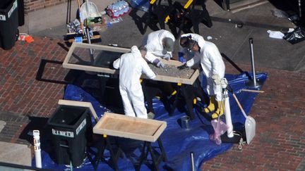 Des enqu&ecirc;teurs inspectent, jeudi 18 avril 2013, les restes d'une bombe qui a explos&eacute; lors du marathon de Boston (Etats-Unis), trois jours auparavant. (DARREN MCCOLLESTER / GETTY IMAGES NORTH AMERICA / AFP)