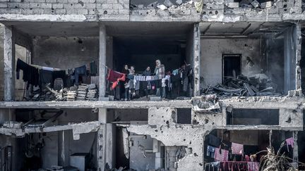 Une famille se tient dans les décombres d'un immeuble, à Rafah, dans le sud de la bande de Gaza, le 21 février 2024. (ABED ZAGOUT / ANADOLU / AFP)