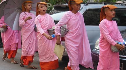 De fait traitées comme des êtres inférieurs aux hommes, les femmes peuvent cependant devenir moines. En matière spirituelle, cependant, elles seraient les égales des hommes. Comme leurs homologues masculins, elles pratiquent la méditation et l’étude des textes sacrés. Comme eux, elles se rasent le crâne. Habillées d’une robe rose, elles doivent, elles aussi, mendier leur subsistance. Comme ici dans les rues de Yangon.
  (France Télévisions)