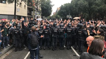 Des policiers bloquent des habitants à Barcelone, dimanche 1er octobre. (ROBIN PRUDENT / FRANCEINFO)