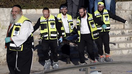 Des secouristes emportant les restes d'un des Palestiniens qui a tué une policière à Jérusalem (Israël), avant d'être abattu, le 3 février 2016. (AHMAD GHARABLI / AFP)