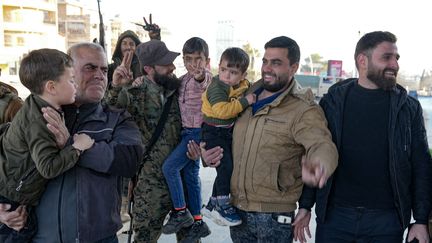 Des habitants accueillent des combattants anti-gouvernementaux dans le centre d'Alep, le 30 novembre 2024. (MUHAMMAD HAJ KADOUR / AFP)