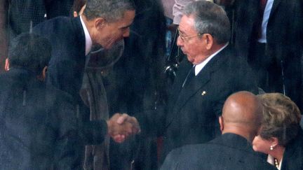 Le pr&eacute;sident am&eacute;ricain Barack Obama (G) sert la main de son homologue cubain Raul Castro &agrave; l'occasion de l'hommage international rendu &agrave; Nelson Mandela dans le stade de Johannesbourg (Afrique du sud), le 10 d&eacute;cembre &nbsp;2013. (CHIP SOMODEVILLA / GETTY IMAGES)