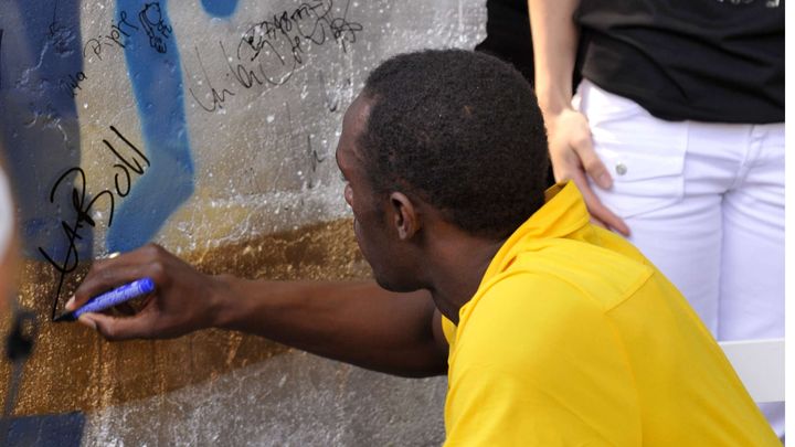 Usain Bolt signe le morceau du mur de Berlin qui lui a &eacute;t&eacute; offert apr&egrave;s les championnats du monde d'athl&eacute;tisme dans la capitale allemande, le 23 ao&ucirc;t 2009. (GERO BRELOER /AP / SIPA / AP)