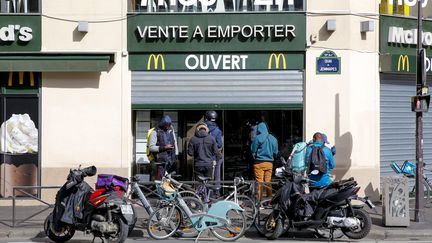 Des livreurs devant le Mc Donald's, fermé au public à cause du coronavirus, le 15 mars 2020 à Paris. (S?BASTIEN MUYLAERT / MAXPPP)