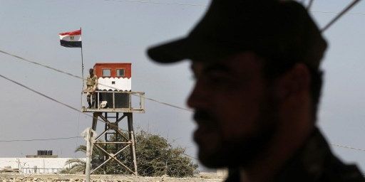 Rafah, dans la bande de Gaza, à la frontière avec l'Egypte, le 5 Juillet 2013. Un policier du Hamas fait face à un soldat égyptien qui surveille la frontière du haut d'une tour de guet. (AFP PHOTO / SAID KHATIB)