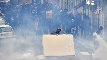 Un manifestant se protège avec un matelas des gaz&nbsp;lacrymogènes jetés par la police, le 31 mars 2016 à Nantes. (LOIC VENANCE / AFP)