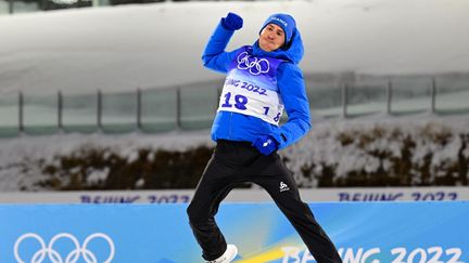 Quentin Fillon Maillet saute&nbsp;de joie sur le podium après la conquête de sa troisième médaille en biathlon à Pékin, en sprint, le 12 février 2022. (TOBIAS SCHWARZ / AFP)