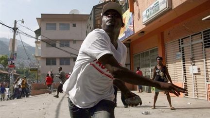 Un protestataire lance des pierres sur les casques bleus à Pétion-Ville, le 12/08/2010 (AFP/Hector Retamal)