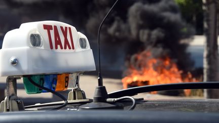 Des pneus br&ucirc;lent pendant une manifestation de chauffeurs de taxi, &agrave; Paris, le 25 juin 2015. (ANNE-CHRISTINE POUJOULAT / AFP)