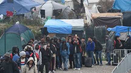 Des migrants attendent à l'entrée du "sas" prévu pour les orienter, pendant l'évacuation de la "jungle" de Calais, le 24 octobre 2016, à Calais. (FRANCOIS LO PRESTI / AFP)