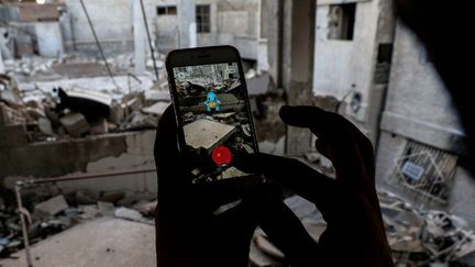 Un utilisateur de Pokémon Go dans les décombres de la ville de Douma, près de Damas en Syrie. (Sameer Al-Doumy / AFP)