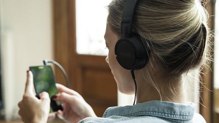 Une femme écoute de la musique sur son smartphone.&nbsp; (SIGRID OLSSON / MAXPPP)