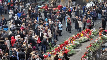 Des Ukrainiens se recueillent place de l'Ind&eacute;pendance &agrave; Kiev (Ukraine), le 23 f&eacute;vrier 2014. (GENYA SAVILOV / AFP)