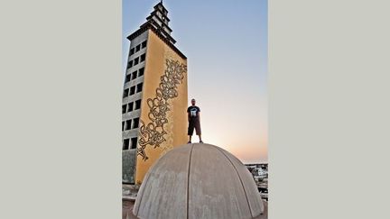 el Seed devant le minaret de la mosquée de Gabès, posant devant l'un de ses graffitis. (DafoxInDaBox)