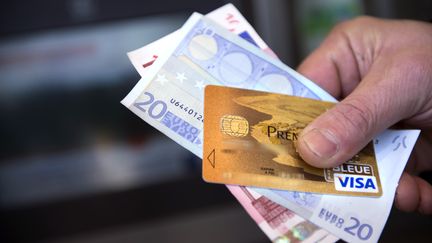 Un homme tient une carte de cr&eacute;dit et des billets de banque, le 5 f&eacute;vrier 2013 &agrave; Tours (Indre-et-Loire). (ALAIN JOCARD / AFP)