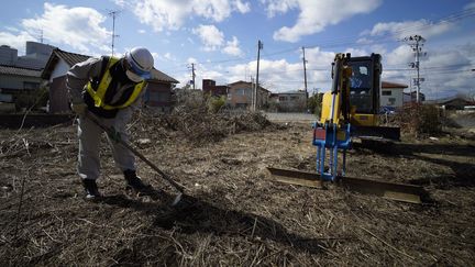 Des travailleurs chargés de la décontamination, retire du sol irradié à Namie, à huit kilomètres de la centrale nucléaire de Fukushima (Japon), le 24 février 2016. (FRANCK ROBICHON / EPA)