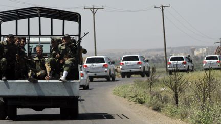 Des soldats syriens escortent le convoi des observateurs de l'ONU juste avant l'explosion qui a bless&eacute; six soldats &agrave; Deraa (Syrie), le 9 mai 2012. (LOUAI BESHARA / AFP)