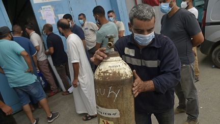 Des Algériens attendent de recevoir des bouteilles d'oxygène offertes par une entreprise privée pour les patients atteints de Covid-19&nbsp;à Blida, au sud d'Alger, le 28 juillet 2021. (RYAD KRAMDI / AFP)